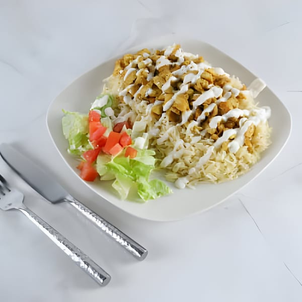 US Fried Chicken's chicken over rice with white sauce, lettuce, and diced tomatoes, with cutlery.