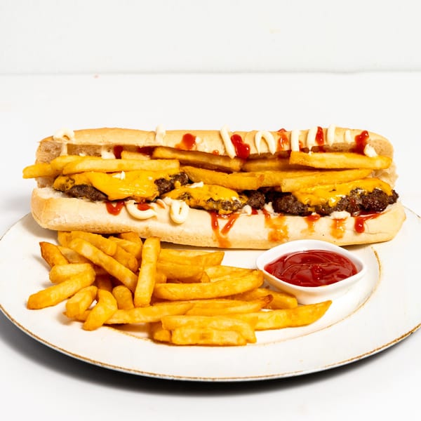 A long cheeseburger sub with fries, ketchup, and mayonnaise, served with a side of fries and ketchup.