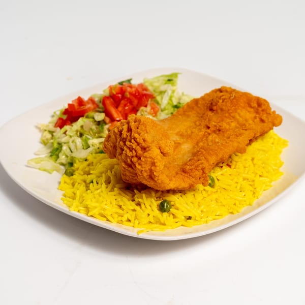 Crispy fried chicken fillet on a bed of yellow rice with green peas, served with a side salad.