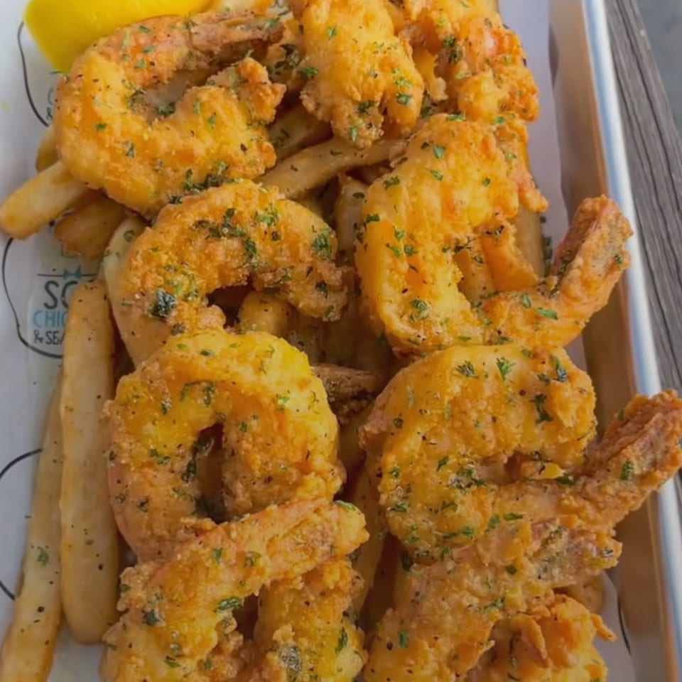 Golden-brown fried shrimp and french fries, garnished with parsley and a lemon wedge.