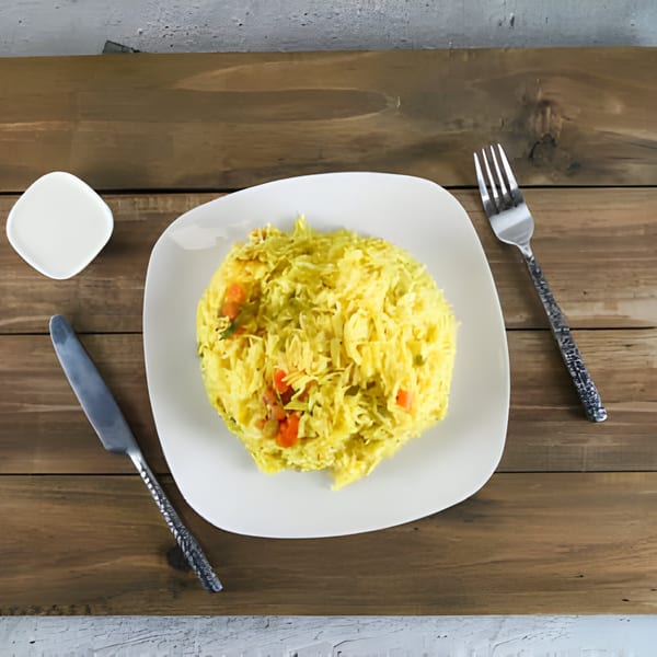 Yellow rice with diced vegetables on a white plate, with a knife and fork.