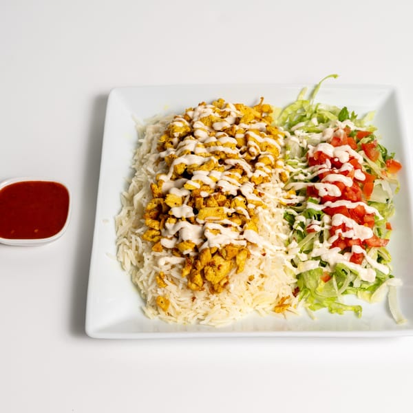 US Fried Chicken's chicken over rice with salad and a side of red sauce.