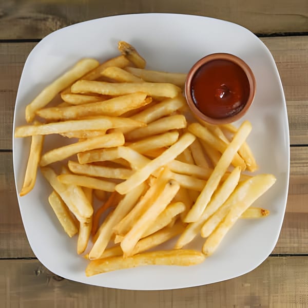 A white plate filled with golden french fries and a small bowl of ketchup on a wooden table.