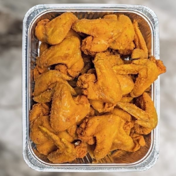 A foil tray filled with golden-brown, crispy fried chicken wings from US Fried Chicken.