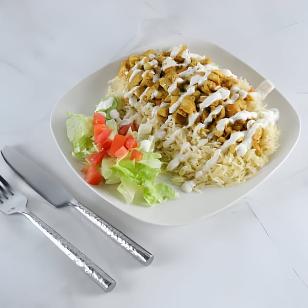 US Fried Chicken's fried chicken and rice platter with salad, drizzled with white sauce.