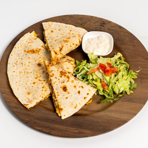 Chicken quesadillas with a side salad and dipping sauce on a wooden plate.