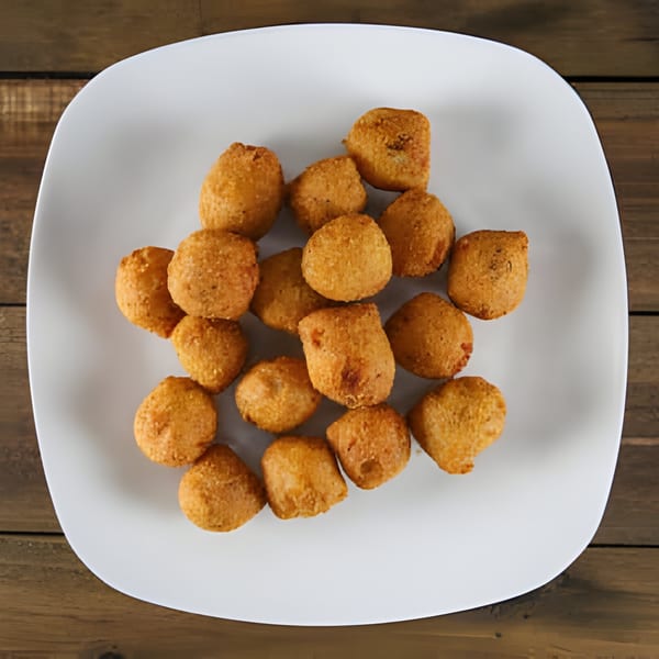 A white square plate filled with golden-brown fried chicken nuggets on a wooden table.