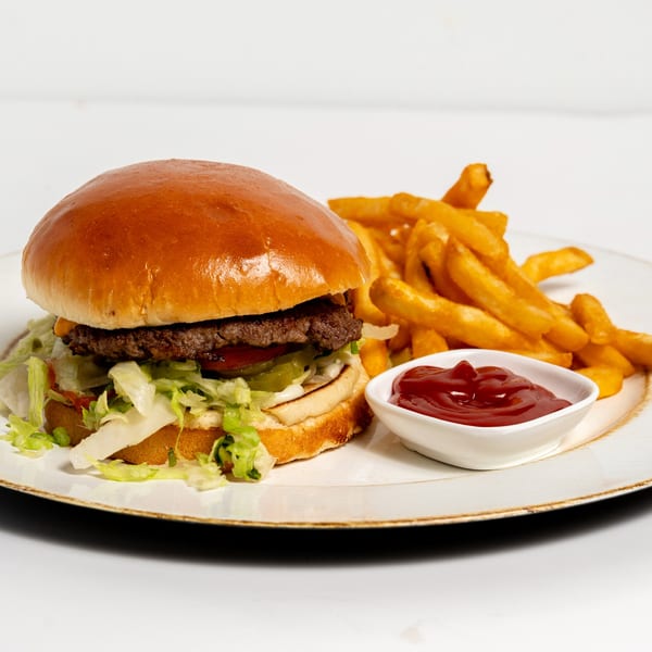 A beef burger with lettuce, tomato, and pickles, served with golden fries and ketchup.