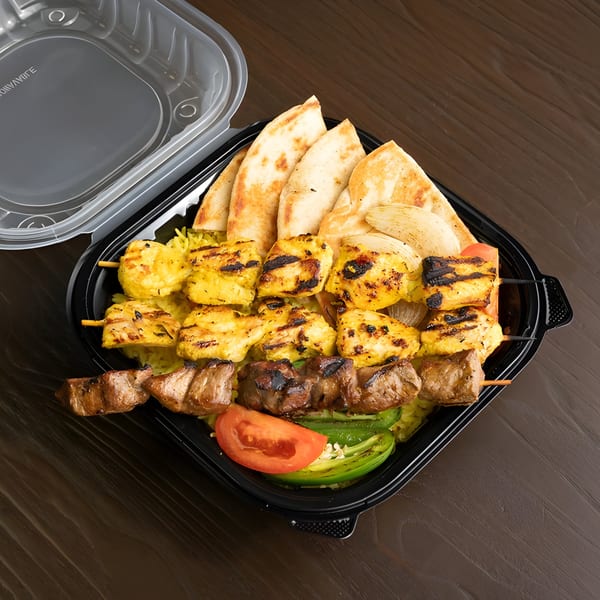 Chicken and beef skewers with rice, pita bread, tomato, and jalapeño in a black takeout container.