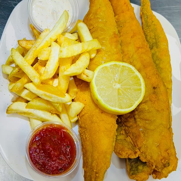 Golden fried fish fillets with a lemon slice, french fries, tartar sauce, and salsa on a white plate.